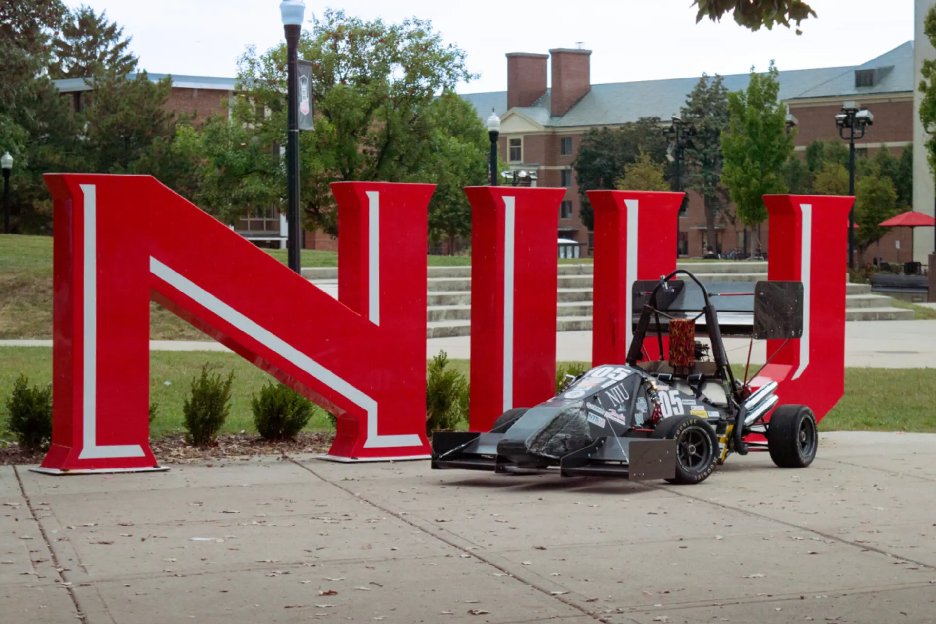 The 2025 Huskie Motorsports car posed in front of a bright red N.I.U. logo.